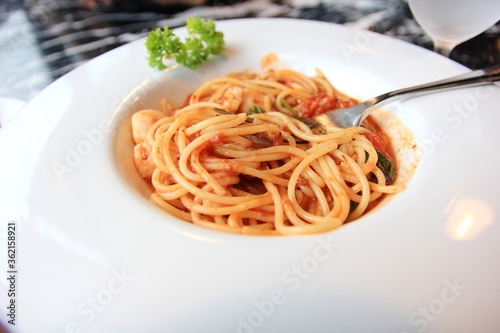 Spaghetti with shrimp in white disc on marble table