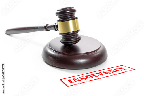 Judge gavel and a red stamp with the word Insolvency, companies are going bankrupt due to the coronavirus crisis, isolated on a white background