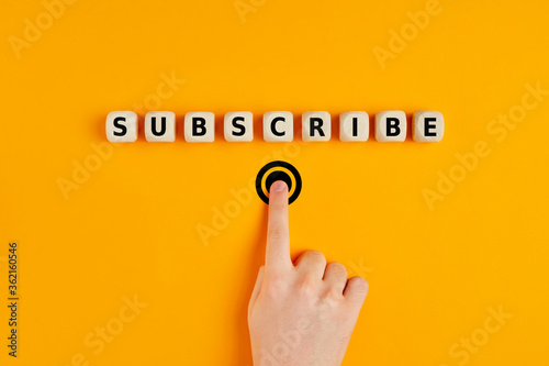 Male hand pressing subscription button with the word subscribe written on wooden blocks. Concept of online registration. photo
