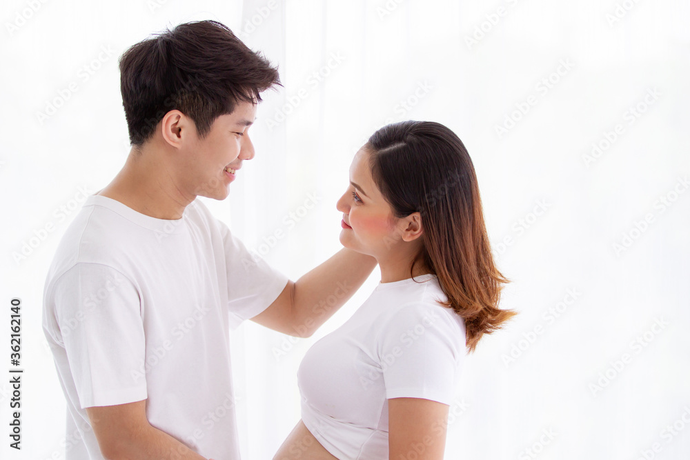 Asian lovely husband and wife portrait, his wife is in pregnancy. Husband tenderly hug and kiss his wife on the bed with care. Husband embracing his pregnant wife and making their hands in heart shape Asian lovely husband and wife portrait, his wife is in pregnancy. Husband tenderly hug and kiss his wife on the bed with care. Husband embracing his pregnant wife and making their hands in heart shape