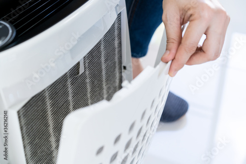 Schilderij op canvas Asian woman changing the dirty air purifier filter after using for a long time in the dirty air environment