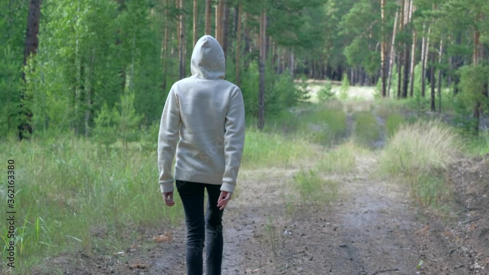 Anonymous person in the hood throws a plastic bottle in the woods. Environmental pollution with plastic. Caring for nature. Anonymous person in the hood throws a plastic bottle in the woods. Environmental pollution with plastic. Caring for nature.