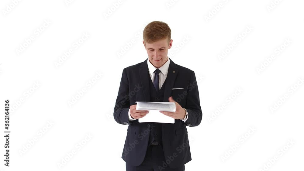A young, handsome man in a jacket checks documents, payments, a report. Businessman isolated on a white background. He is pleased with the work of the corporate staff. He smiles and enjoys looking at A young, handsome man in a jacket checks documents, payments, a report. Businessman isolated on a white background. He is pleased with the work of the corporate staff. He smiles and enjoys looking at
