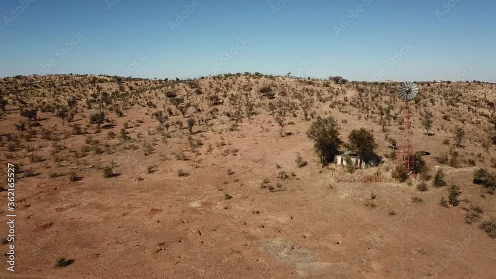 4K aerial drone video of Africa savanna hills, plains and farm wind water pumps on pillars in dry riverbed near Neuheusis west of Windhoek in central highland of Namibia, southern Africa