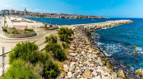 A panorama across the breakwater on Ortygia island towards the harbour entrance of Syracuse, Sicily in summer photo