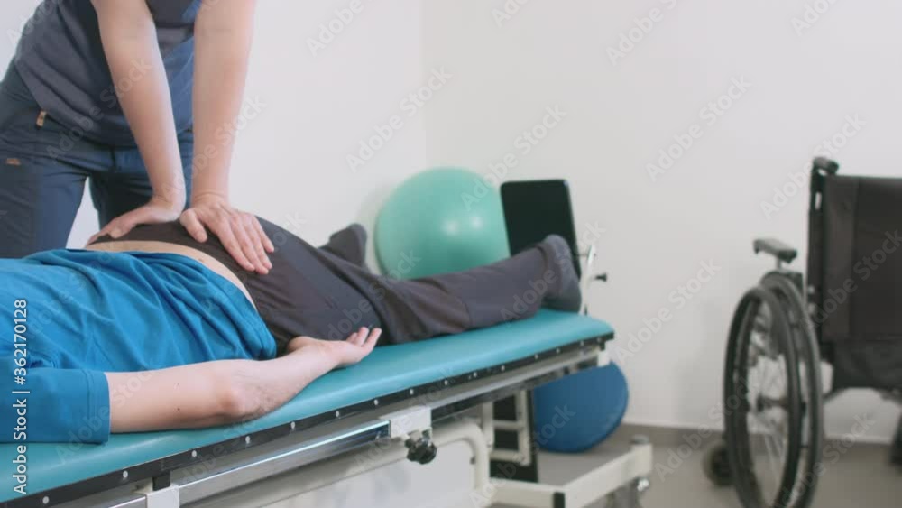 Physiotherapist exercising with disabled person on a therapy table. Physiotherapist exercising with disabled person on a therapy table.