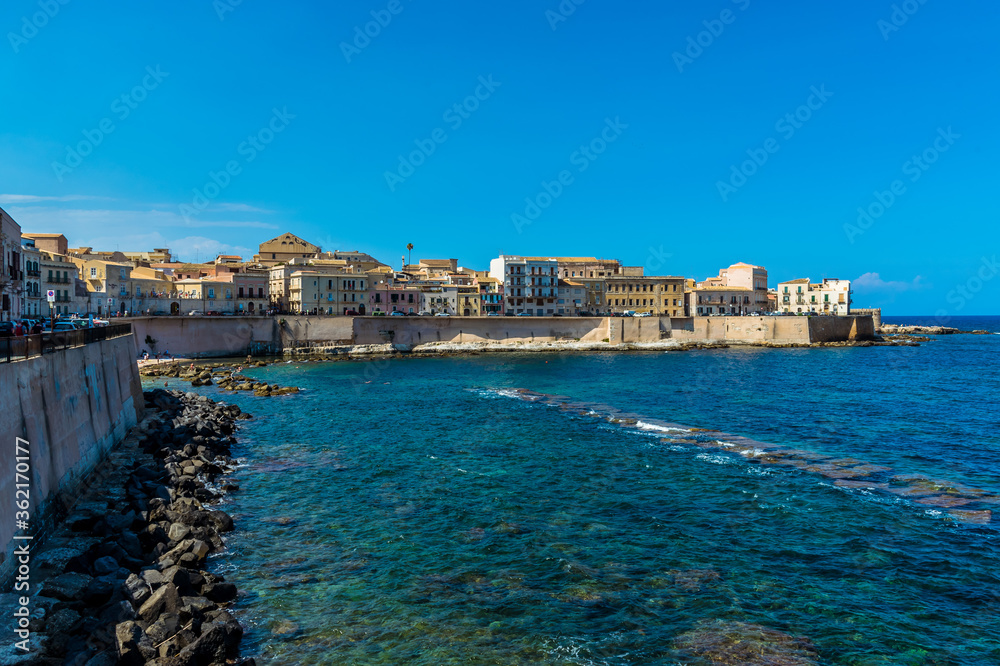 Naklejka premium A view along the shoreline towards Fort Vigliena on Ortygia island in Syracuse, Sicily in summer