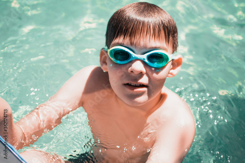 Boy in swimming glasses swims in the pool. Swimming in the pool. Summer activities.