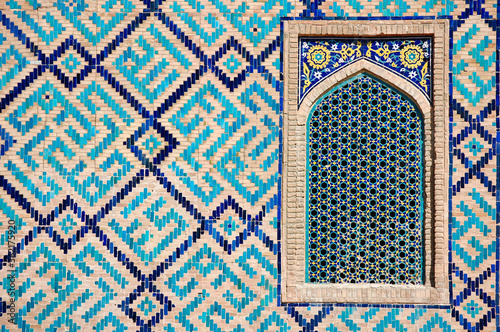 Detail of turquoise, yellow and blue tiling and window on a the exterior wall of a madrassa in Samarkand's ancient Registan complex in Uzbekistan.