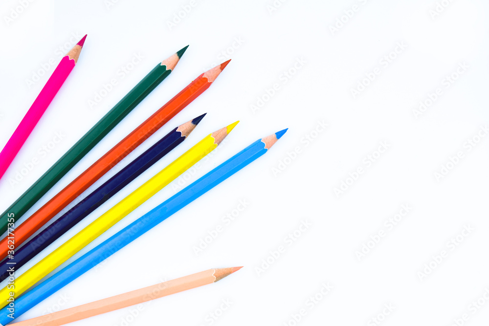 Six different colored wood pencil crayons scattered on a white background