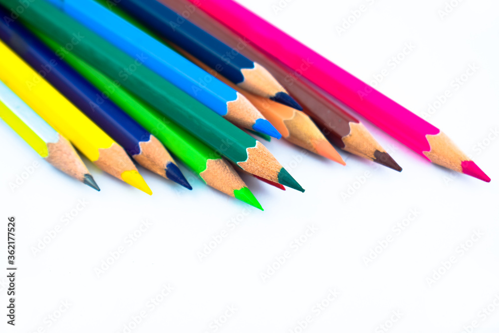 Stack of different colored wood pencil crayons scattered across a white background Stack of different colored wood pencil crayons scattered across a white background
