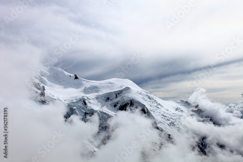 Mont Blanc Covered with snow and clouds. Single mountain peak. Snowy mountain summit. White mountain top on a cloudy day. Snow-covered white mountain peak. Mountains landscape. Climbing mountains.