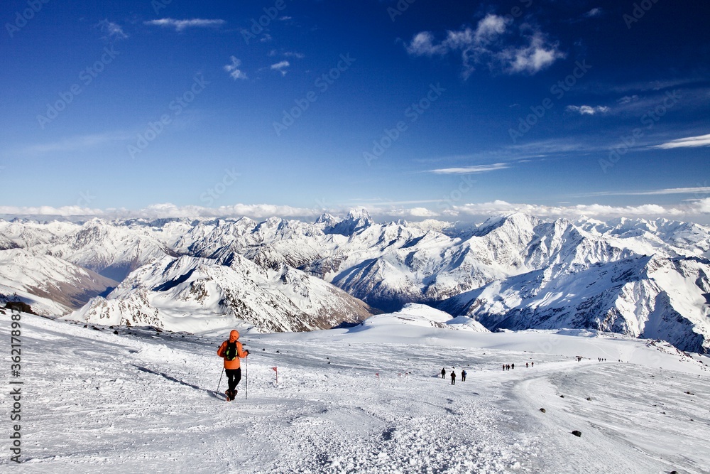 A group of Climbers Hiking high in the mountains in sunny day. Hiking trail among Snow-covered white mountain peaks. Sport in the Mountains. People climbing to the top of the snowy mountain. A group of Climbers Hiking high in the mountains in sunny day. Hiking trail among Snow-covered white mountain peaks. Sport in the Mountains. People climbing to the top of the snowy mountain.