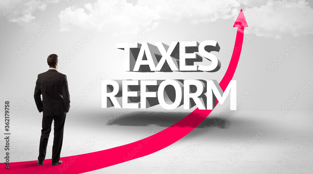 Fototapeta premium Rear view of a businessman standing in front of TAXES REFORM inscription, successful business concept