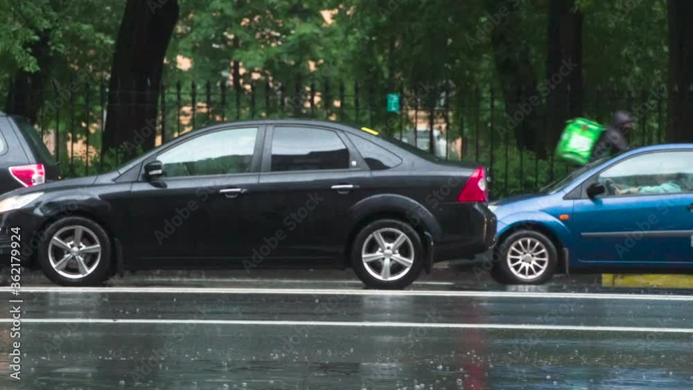 Rainy Weather in the City. The car moves past the camera and rides through the puddle. From under the wheel rises a beautiful stream of water. Filmed at a speed of 240fps Rainy Weather in the City. The car moves past the camera and rides through the puddle. From under the wheel rises a beautiful stream of water. Filmed at a speed of 240fps