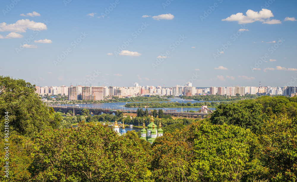 Landscape view of the left side of Kyiv on Dnipro river in the botanical garden and St. Michael's Vydubytsky Men's Monastery and Patona bridge located in Ukraine Europe