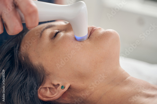 Convenient hand probe used on the face of woman in clinic