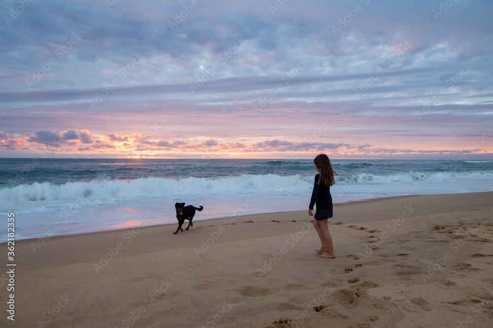 cute little girl running on the beach with her dog at sunset cute little girl running on the beach with her dog at sunset