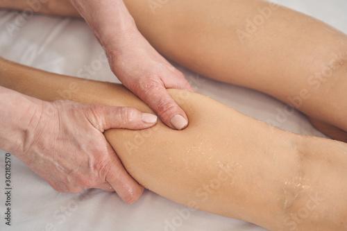 Hands of professional doing massage of legs in spa salon