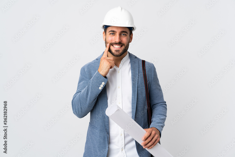 Young architect man with helmet and holding blueprints isolated on white background smiling with a happy and pleasant expression Young architect man with helmet and holding blueprints isolated on white background smiling with a happy and pleasant expression
