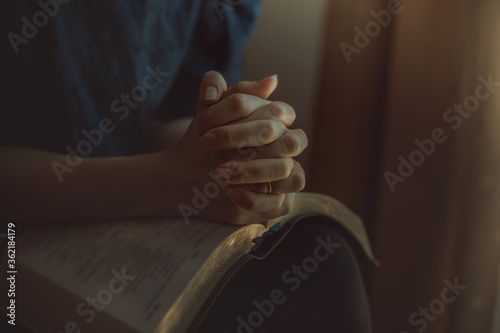 Close up of woman hands praying on bible.