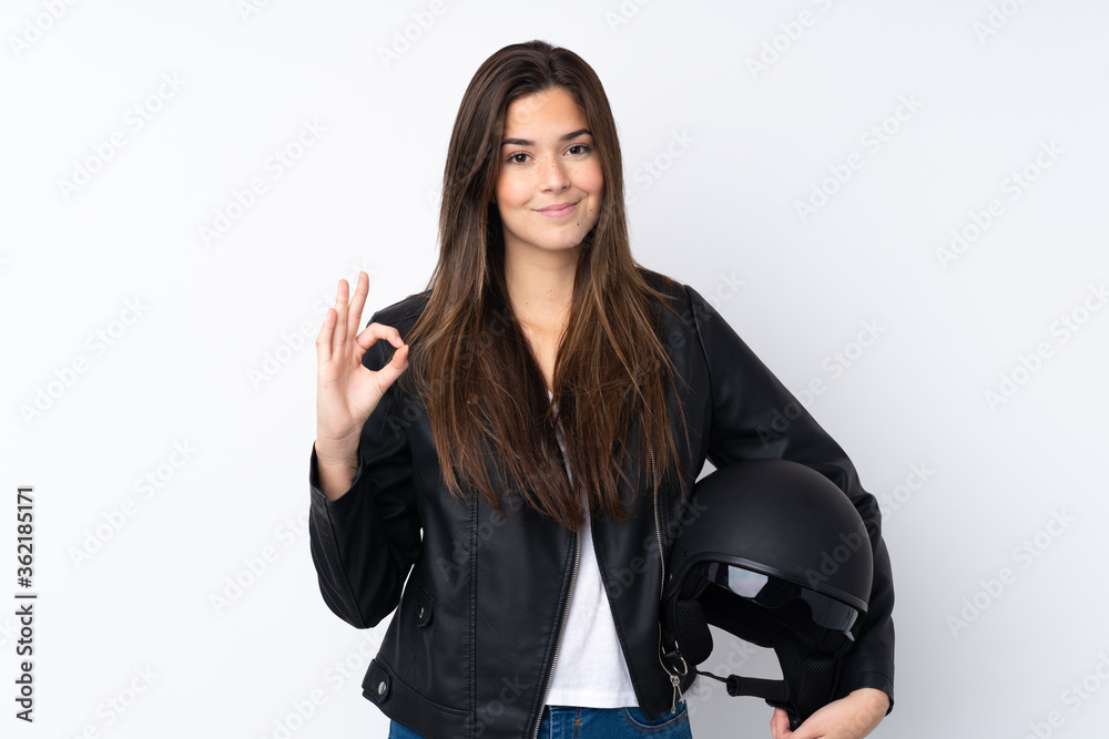 Young woman with a motorcycle helmet over isolated white background showing an ok sign with fingers Young woman with a motorcycle helmet over isolated white background showing an ok sign with fingers