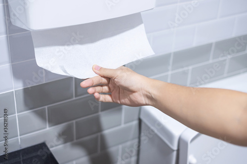 Woman hand pulling toilet paper in restroom. Cleaning, Lifestyle and personal hygiene concept
