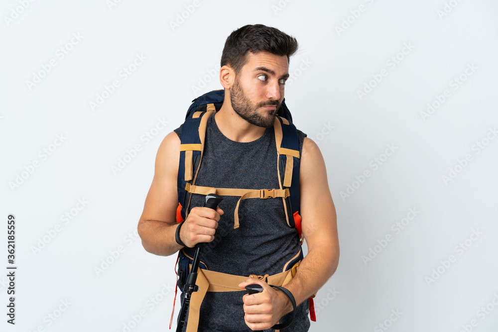 Young mountaineer man with a big backpack and trekking poles isolated on white background thinking an idea Young mountaineer man with a big backpack and trekking poles isolated on white background thinking an idea