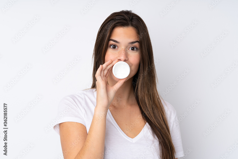 Teenager girl over isolated background with moisturizer Teenager girl over isolated background with moisturizer