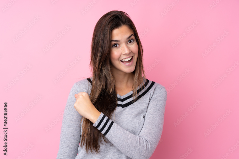 Fototapeta premium Teenager girl over isolated pink background celebrating a victory