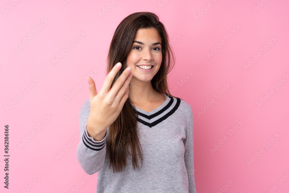 Teenager girl over isolated pink background inviting to come Teenager girl over isolated pink background inviting to come