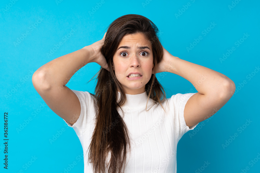 Teenager girl over isolated blue background frustrated and takes hands on head