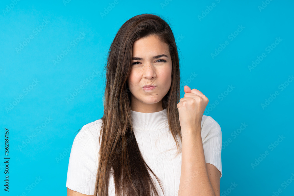 Teenager girl over isolated blue background with angry gesture
