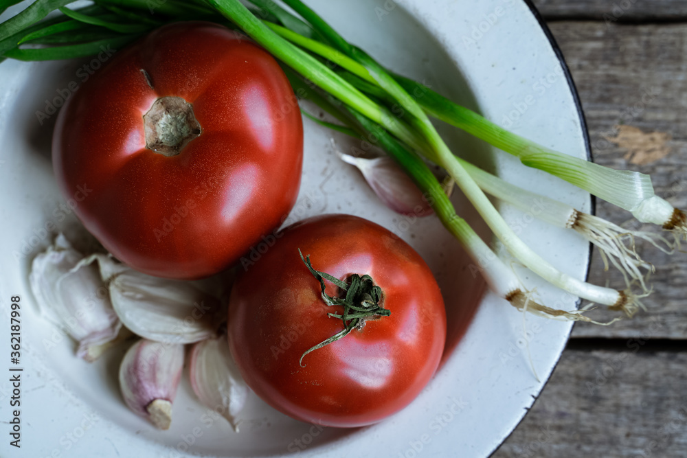 Fresh red tomatoes, garlic, and scallions on old wooden table closeup view Fresh red tomatoes, garlic, and scallions on old wooden table closeup view