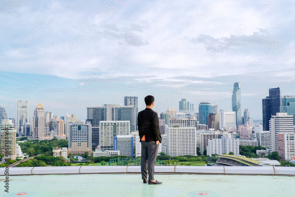 Businessman standing on building. City background with copy space. Success and vision concept