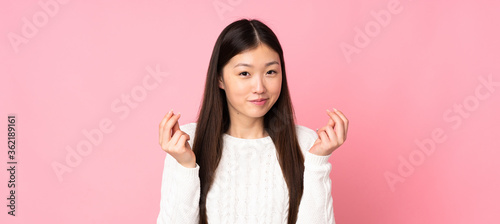 Young asian woman over isolated background making money gesture