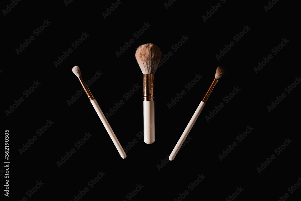 Elegantly lit make-up brushes on a black background