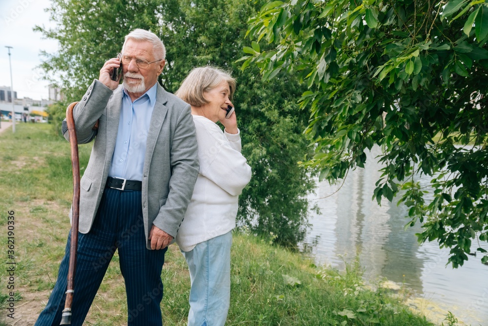 Elderly fashionable couple taking selfie on samrton in the park. Cheerful stylish elderly woman walks in nature. Elderly fashionable couple taking selfie on samrton in the park. Cheerful stylish elderly woman walks in nature.