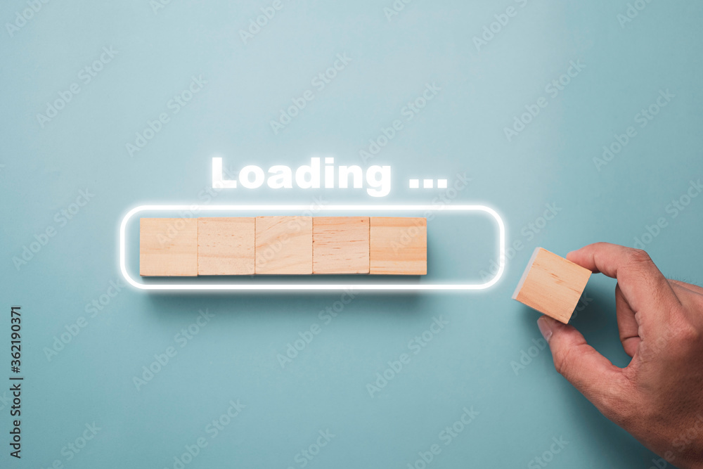 Fotografie Hand putting wooden cube on virtual infographic rectangle block with loading wording