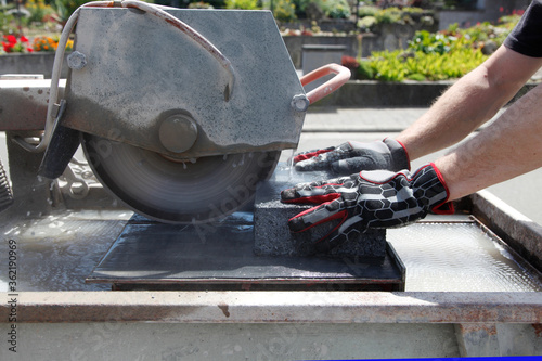 Stone Cutting Machine. Cutting Pavings Stones With a Wet Saw. Side view of a man. Worker hand cutting paver blocks with water cutting machine close-up.