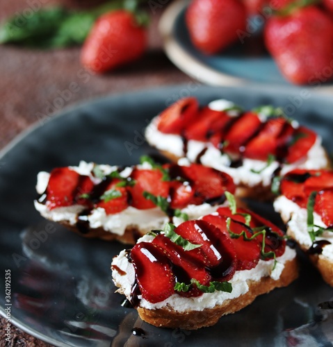 Sandwich with strawberries. With soft cheese and balsamic vinegar. Dark background. Soft focus.