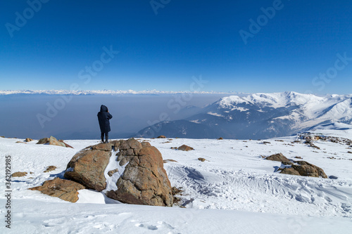 Canvas Print A tourist takes photos of snow covered Himalayan Mountain peaks,