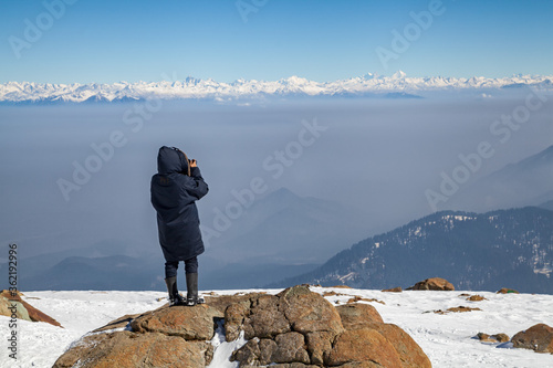 Canvas Print A tourist takes photos of snow covered Himalayan Mountain peaks