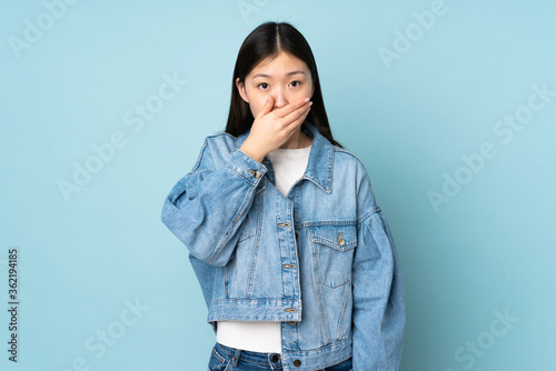 Young asian woman isolated on background covering mouth with hand