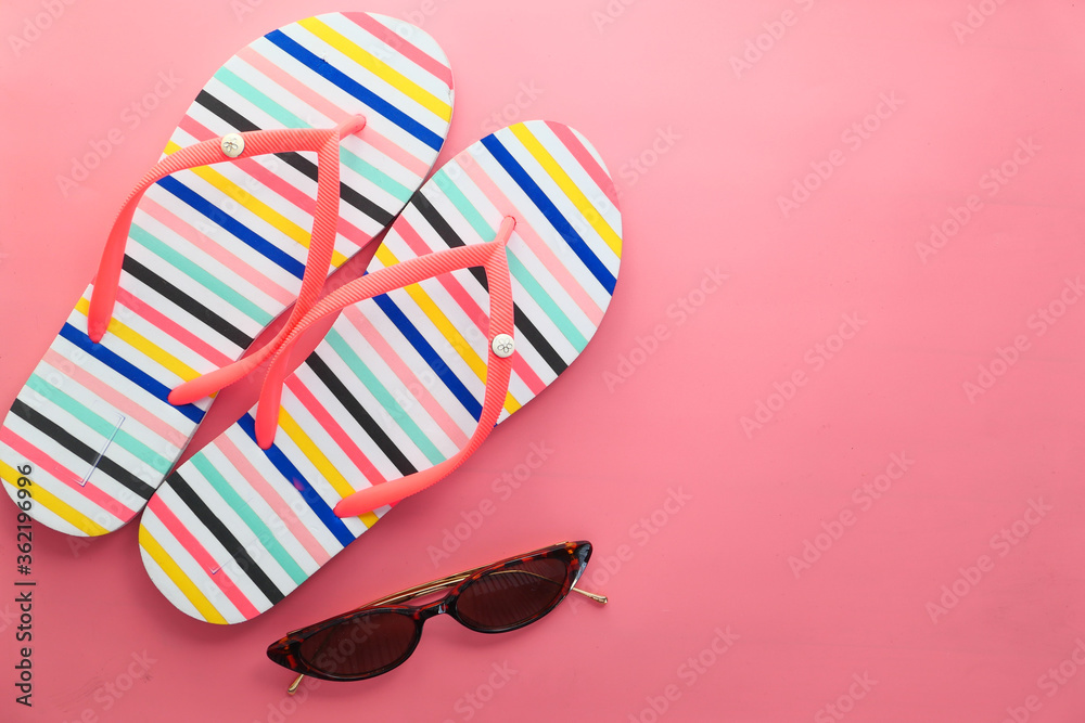Sunglasses and sandals on pink background top down