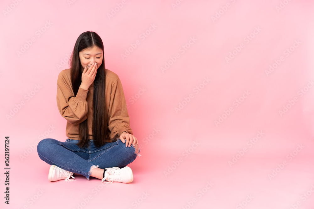 Young asian woman sitting on the floor isolated on pink background smiling a lot Young asian woman sitting on the floor isolated on pink background smiling a lot