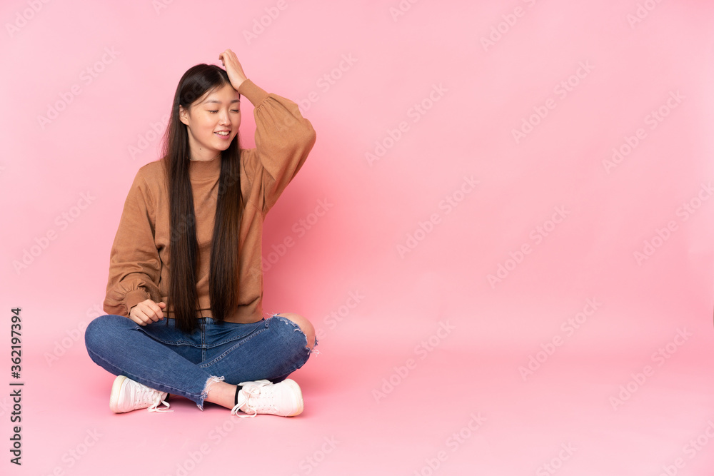 Young asian woman sitting on the floor isolated on pink background has realized something and intending the solution Young asian woman sitting on the floor isolated on pink background has realized something and intending the solution
