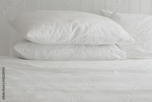 Fototapeta Naklejka Na Ścianę i Meble -  Soft and calm atmosphere image of all white bed room. Pillows and blanket on empty bed, close up.