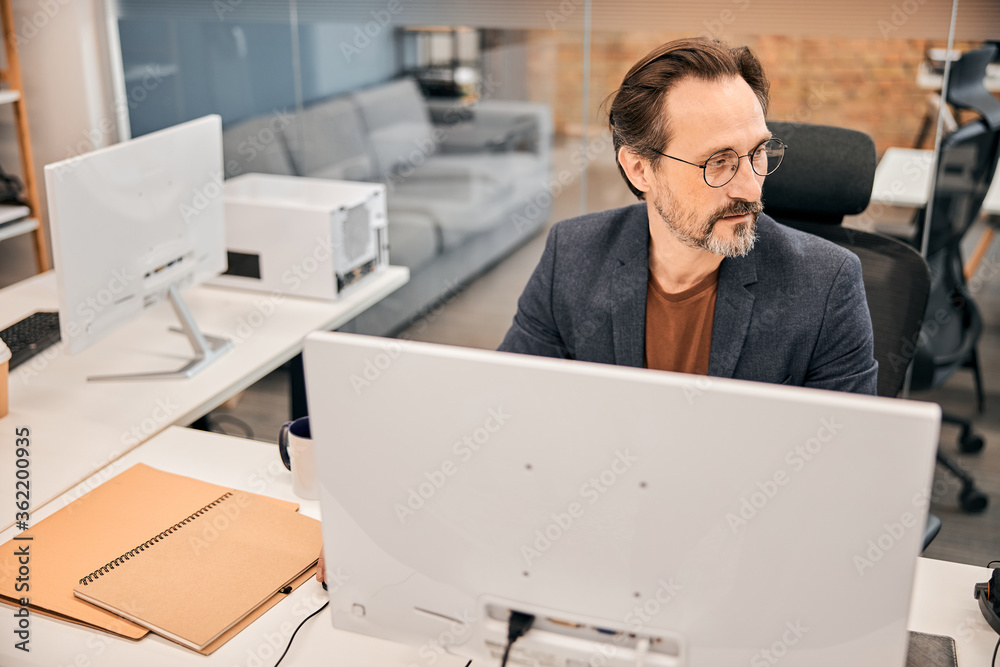 Profile of serious man wearing eyeglasses at his working place Profile of serious man wearing eyeglasses at his working place