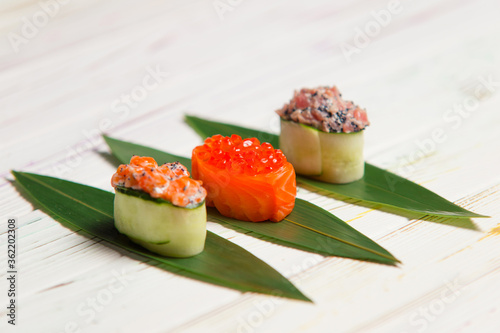 Wallpaper Mural Set of Japanese Gunkan Maki Sushi Rolls: Sake with salmon caviar, tuna Maguro and salmon in cucumber served on bamboo leaves. Pan Asian dishes. Expensive seafood restaurant meal side view
 Torontodigital.ca